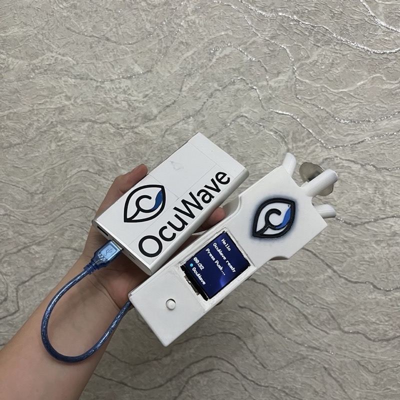 Портативный тонометр OcuWave в руке: корпус с логотипом, OLED-экран и кнопка запуска